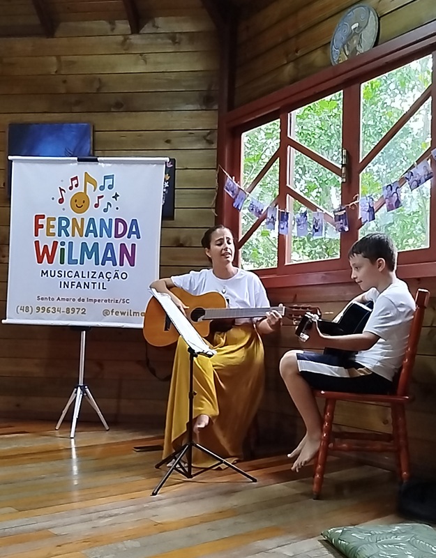 Aluno praticando violão com a professora Fernanda Wilman